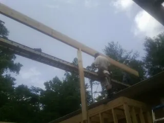 Carpenter setting a ridge beam over a new addition frame — Ice Dam Removal by Roofing Brothers in Barboursville