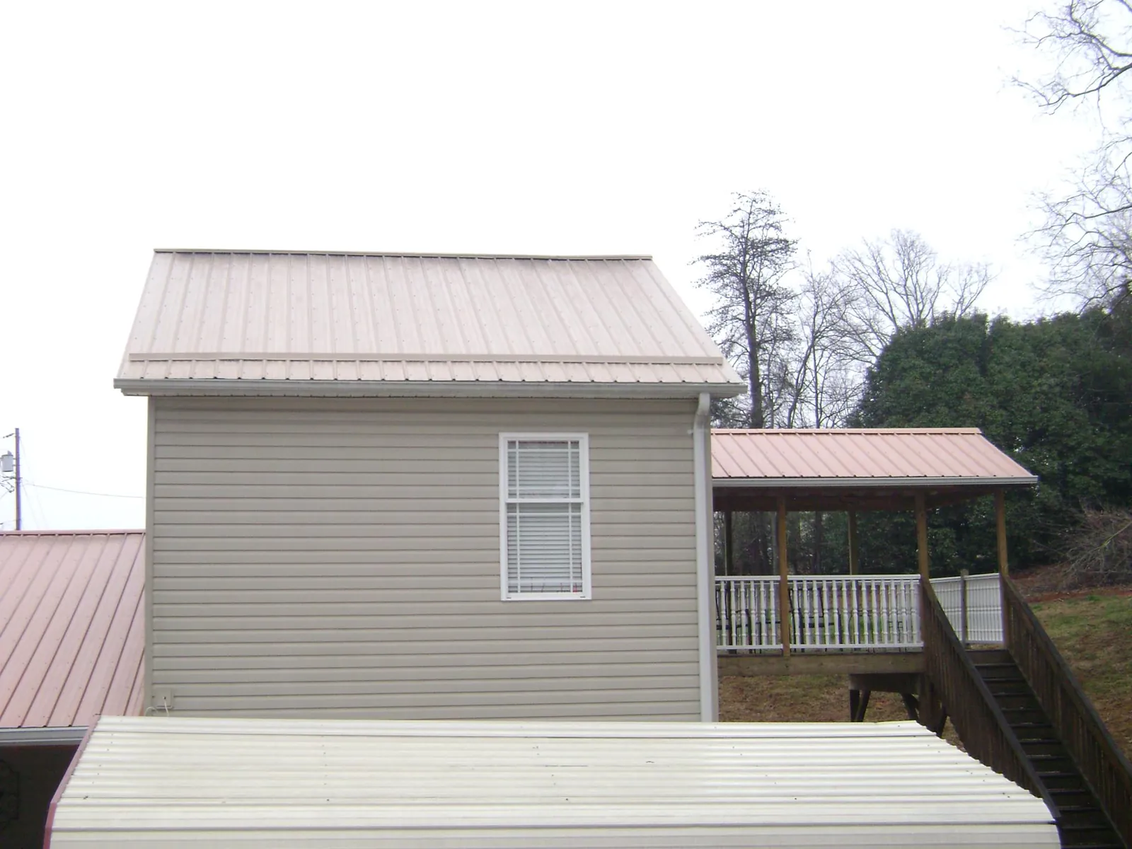 Tan metal roofs on a two story addition and attached porch, from a Roof Replacement job in Barboursville