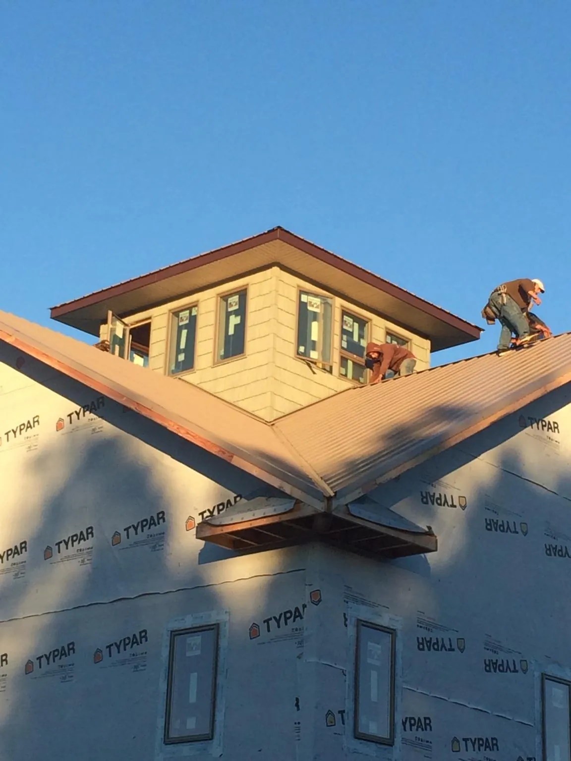 Roofers working around a rooftop cupola on a new metal roof at sunset — Roof Waterproofing in Barboursville by Roofing Brothers
